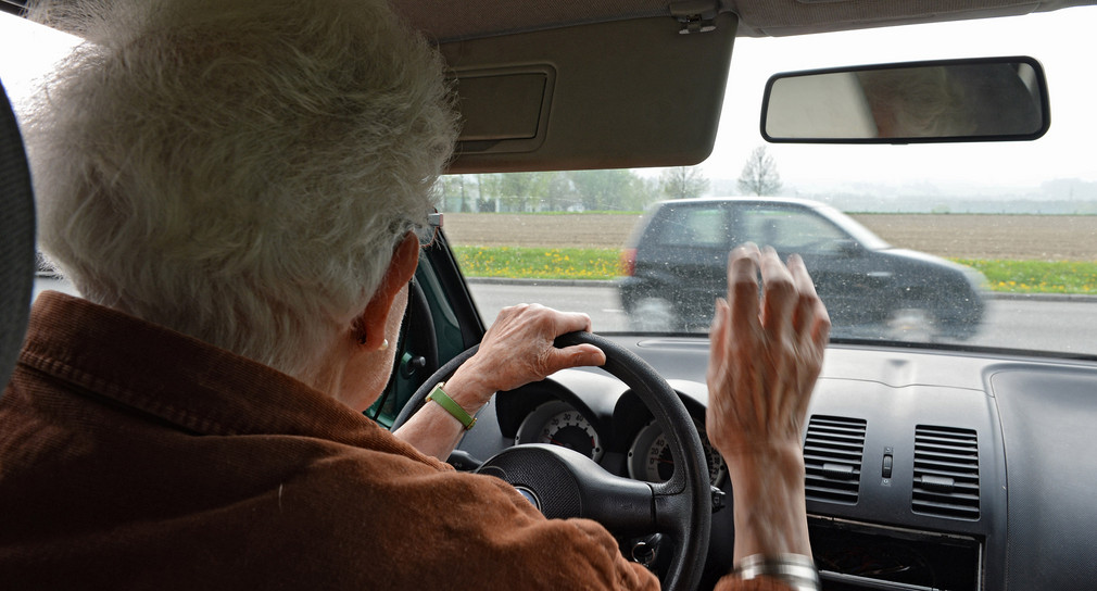 Eine Seniorin sitzt am Steuer ihres Kleinwagens.