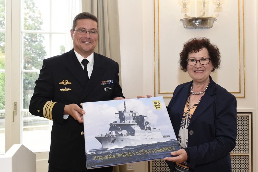 Fregattenkapitän Markus Venker (l.) und Gerlinde Kretschmann (r.) mit einem Foto der Fregatte Baden-Württemberg