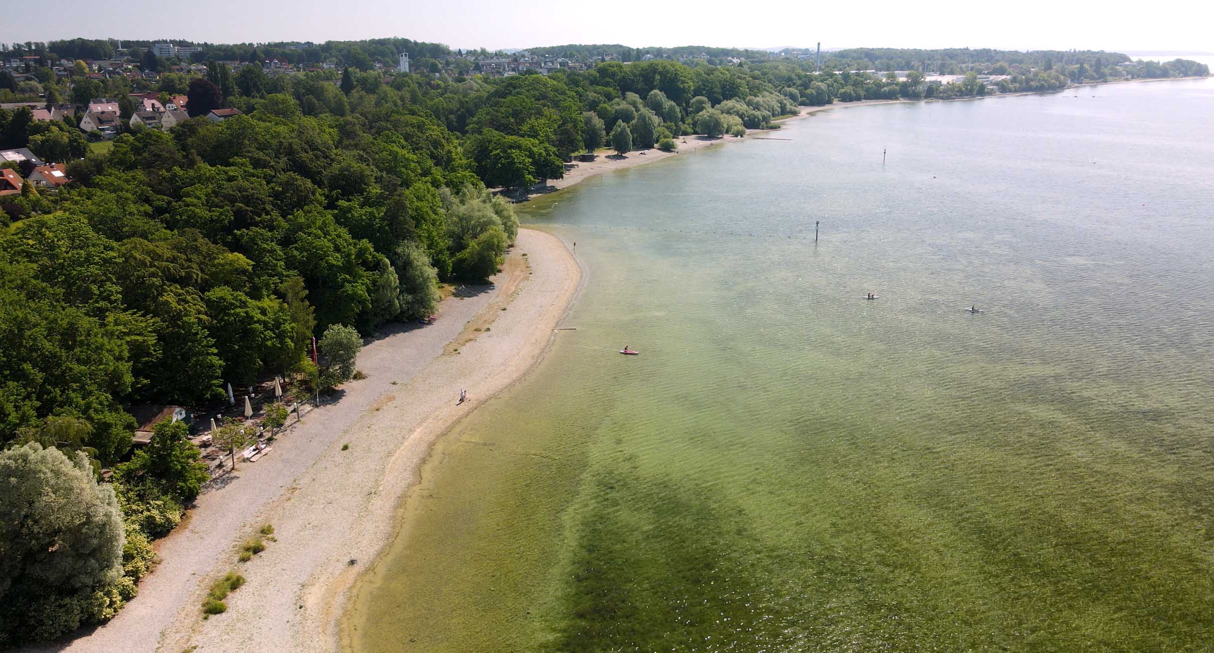 Luftaufnahme des Bodensees mit niedrigem Wasserstand und freigelegtem Uferbereich neben bewaldetem Land