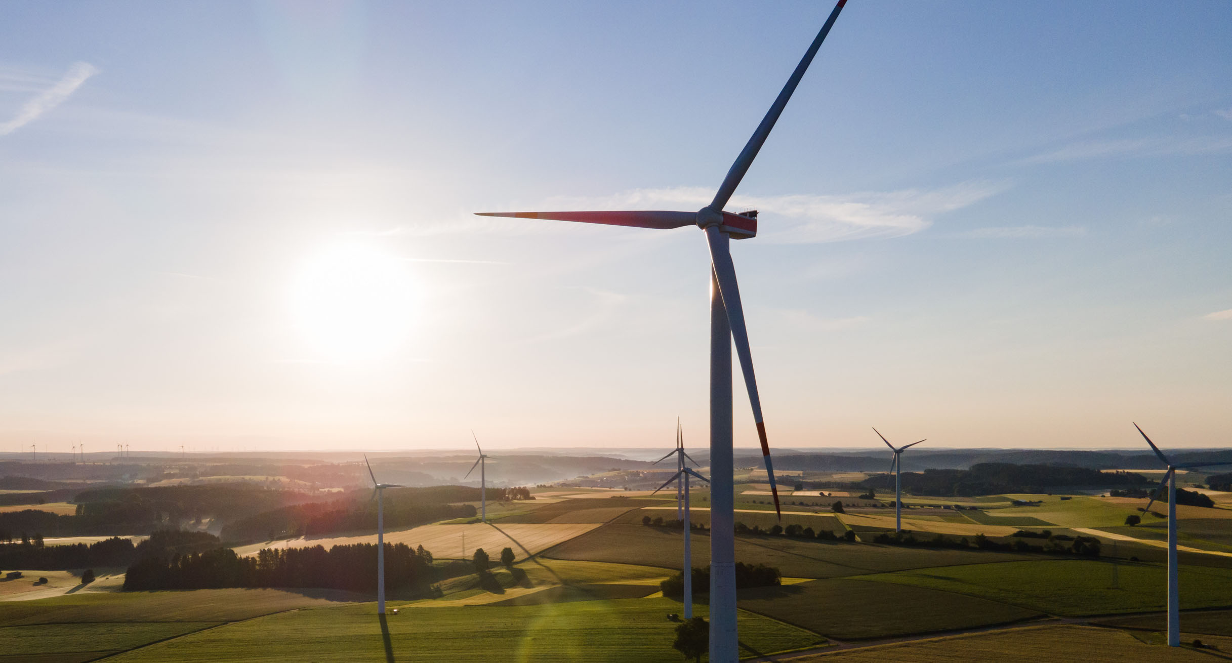 Windräder stehen während des Sonnenaufgangs auf einem Feld.']