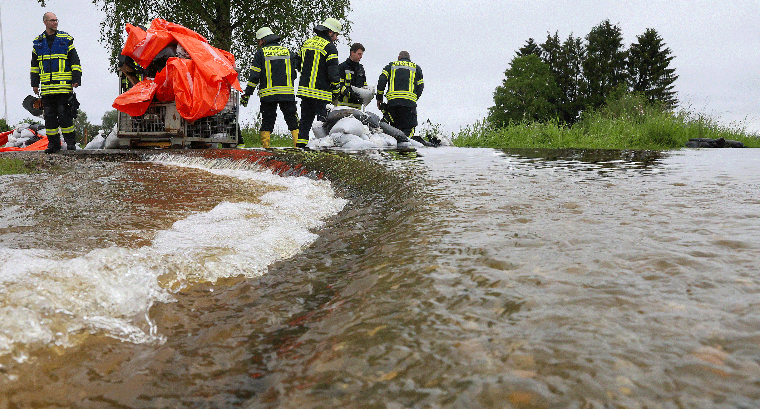 Einsatzkr&auml;fte der Feuerwehr errichten am Nonnenbach in Bad Saulgau im Ortsteil Moosheim einen Damm mit Sands&auml;cken gegen das Hochwasser.