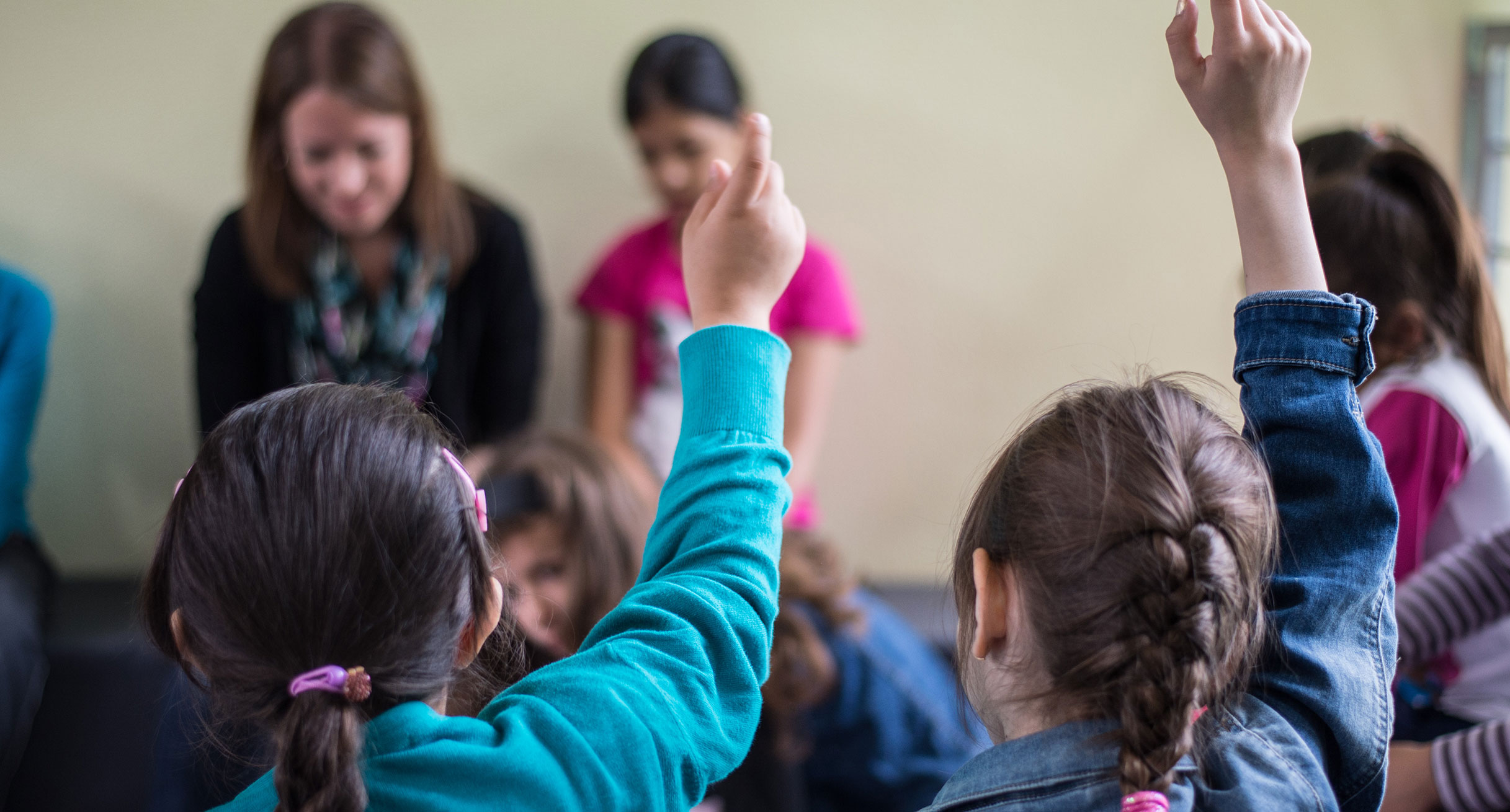 Schülerinnen und Schüler melden sich in einer Klasse.']