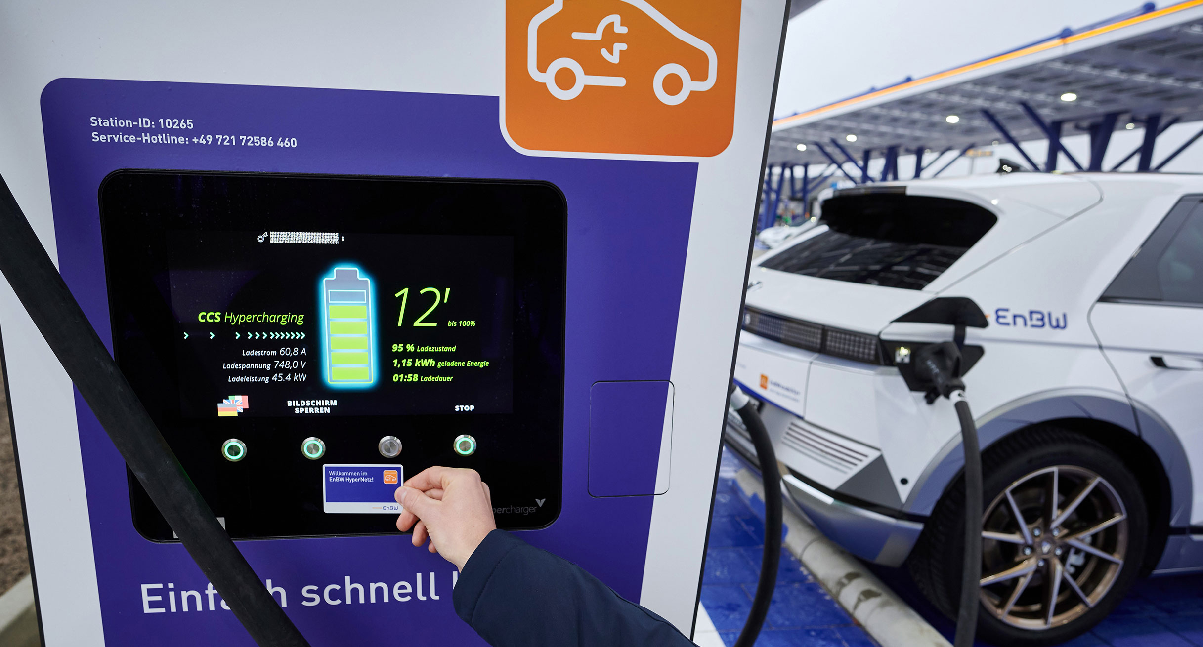 Ein Elektroauto wird an einer Schnellladestation aufgeladen. Auf dem Display kann man den aktuellen Ladestand und andere Ladedaten ablesen.']