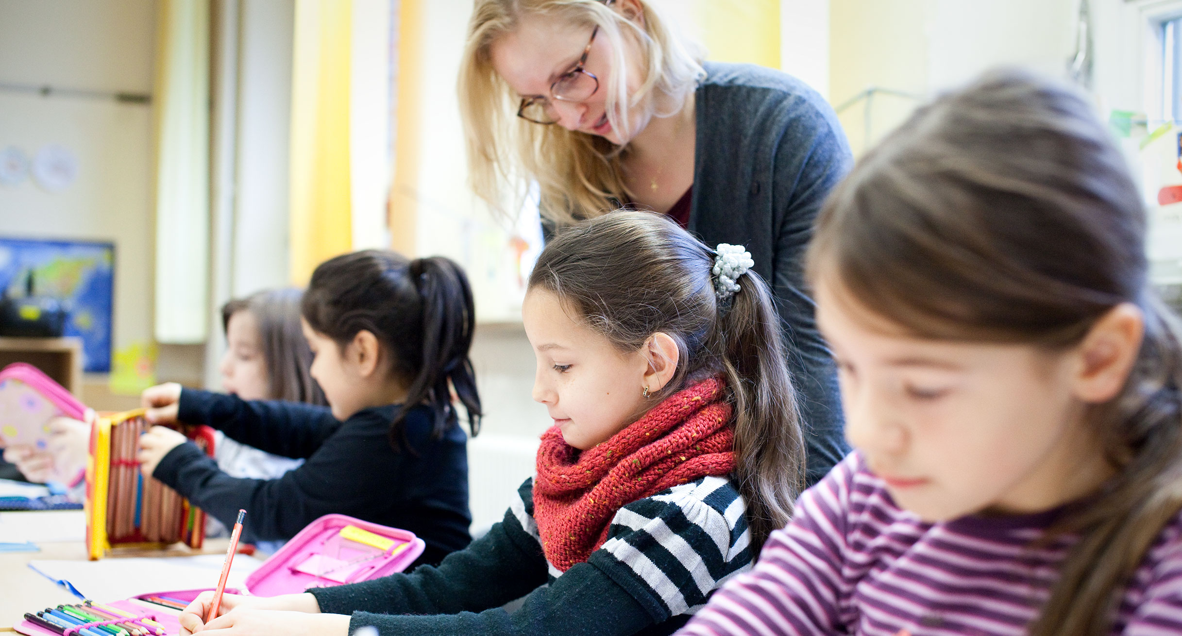 Eine Lehrerin in der Grundschule mit Schülerinnen und Schülern.']