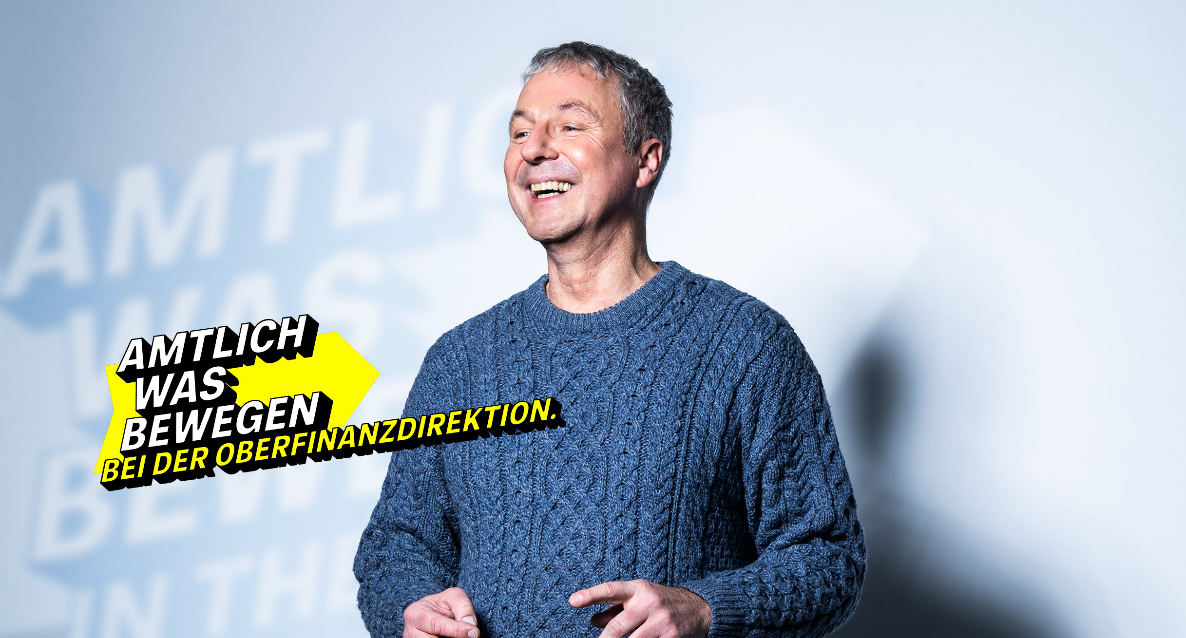 Lächelnder Mann mittleren Alters in einem Strickpullover symbolisiert die Oberfinanzdirektion.