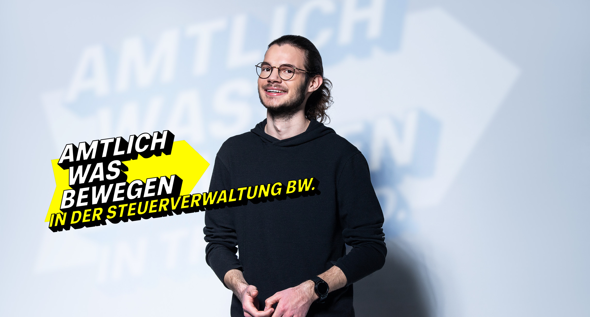 Junger, moderner Mann im schwarzen Pullover steht für die Steuerverwaltung BW.