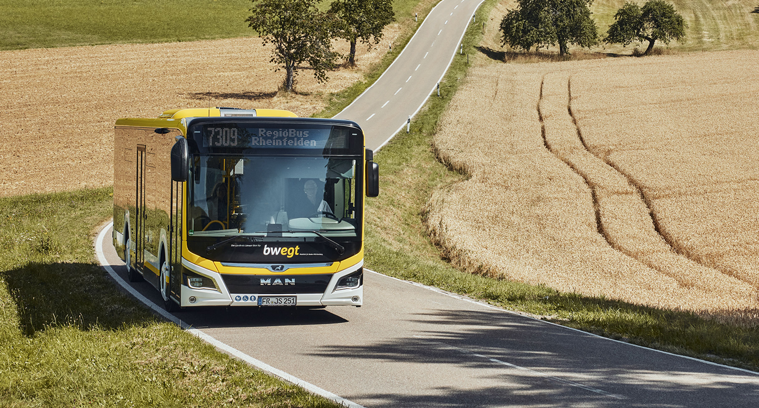 Ein Bus unterwegs auf einer Landstraße.']