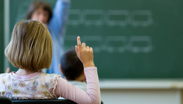 Eine Sch&uuml;lerin meldet sich in einer Schule in Stuttgart w&auml;hrend des Unterrichts.
