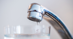 Wasser l&auml;uft aus einem Wasserhahn in ein Glas.