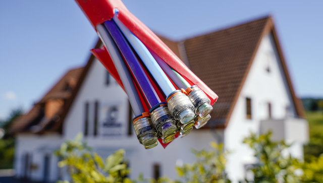 Ein Bündel mit Umhüllungen für Glasfaserkabel hängt vor einem Haus in Oberflockenbach. (Bild: picture alliance/Uwe Anspach/dpa)