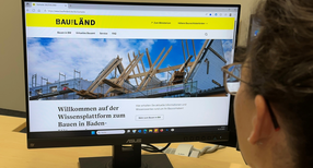 Person vor Computerbildschirm mit BauTheL&auml;nd-Homepage