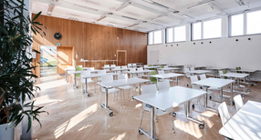 Ein sonnendurchfluteter Schulraum mit Tischen und St&uuml;hlen