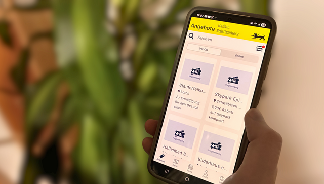 Eine Person h&auml;lt ein Smartphone in der Hand. Auf dem Display sieht man die Startseite der Ehrenamtskarten-App f&uuml;r Baden-W&uuml;rttemberg.