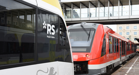 Zwei Züge stehen sich an einem Bahnsteig gegenüber.