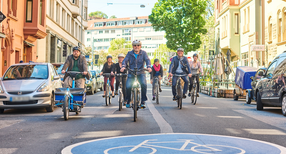 Verkehrsminister Hermann, Amtschef Frie&szlig; sowie Mitarbeiterinnen und Mitarbeiter des Landesradeln durch eine Fahrradstra&szlig;e.