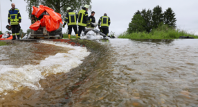 Einsatzkr&auml;fte der Feuerwehr errichten am Nonnenbach in Bad Saulgau im Ortsteil Moosheim einen Damm mit Sands&auml;cken gegen das Hochwasser.