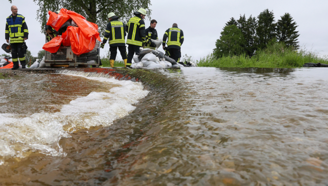Einsatzkr&auml;fte der Feuerwehr errichten am Nonnenbach in Bad Saulgau im Ortsteil Moosheim einen Damm mit Sands&auml;cken gegen das Hochwasser.