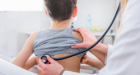 Ein Kinderarzt untersucht einen Jungen mit einem Stethoskop.