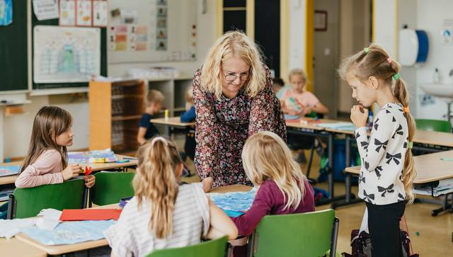 Eine Lehrerin mit Sch&uuml;lerinnen und Sch&uuml;lern in einem Klassenzimmer.