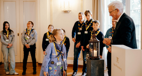Ministerpr&auml;sident Winfried Kretschmann (rechts) mit Pfadfinderinnen und Pfadfindern bei der &Uuml;bergabe des Friedenslichts