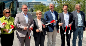 Eine Gruppe aus verschiedenen Politikerinnen und Politikern schneiden auf einer Br&uuml;cke ein Band durch.