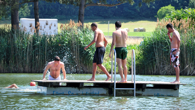 Junge M&auml;nner auf einer Schwimmplattform in einem Badesee in Pl&uuml;derhausen
