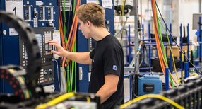 Ein Produktionstechnologe in Ausbildung arbeitet an einem Simulator f&uuml;r die Bewegungseinheit eines Laser.