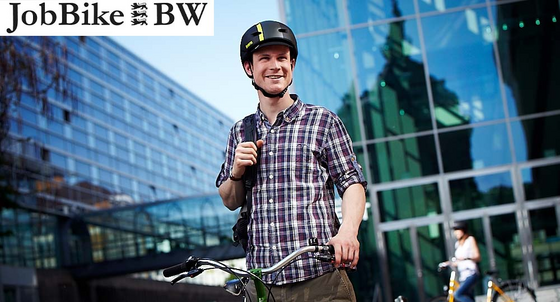 Radfahrer in legerer Arbeitskleidung steht mit Rad und Helm vor einem Bürogebäude