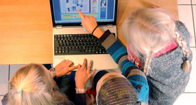 Drei junge M&auml;dchen sitzen an einem Laptop.