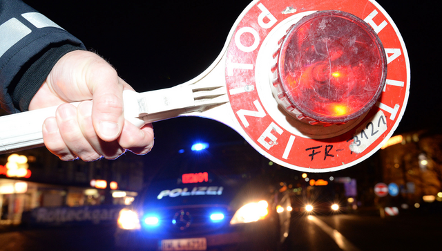 Eine Haltekelle der Polizei ist bei einer Kontrolle vor einem Polizeifahrzeug zu sehen. (Foto: &copy; dpa)