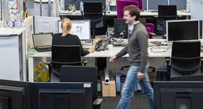 Ein Mitarbeiter geht durch einen B&uuml;roraum.