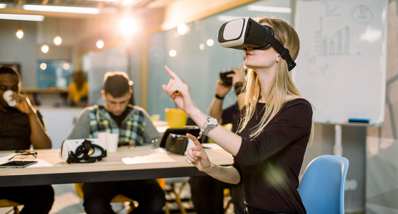 Eine Frau mit einer VR-Brille sitzt in einem großen Gemeinschaftsbüro.