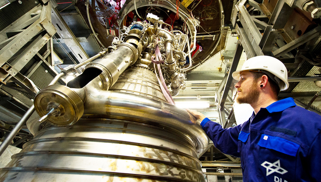 Ein Prüfstandshandwerker begutachtet am Deutschen Zentrum für Luft- und Raumfahrt ein Raketen-Triebwerk